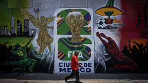 Um homem passa por um mural sobre a Copa do Mundo da FIFA de 2026, na Cidade do México