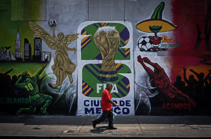 Um homem passa por um mural sobre a Copa do Mundo da FIFA de 2026, na Cidade do México