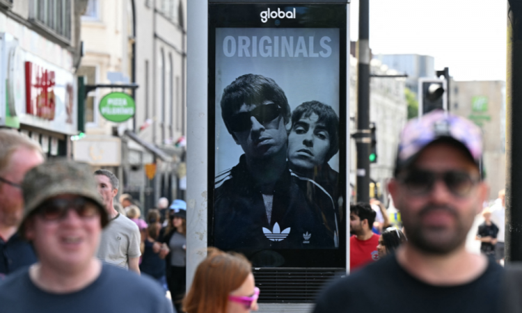 Um anúncio da banda de rock britânica Oasis é visto no centro de Cardiff em 4 de julho de 2025, antes do show de abertura de sua aguardada turnê de reunião, quase 16 anos após a última apresentação. Duas noites consecutivas de shows no Principality Stadium, na capital galesa, marcam o início de uma série de 41 datas de shows espalhados pelo mundo. (Foto de Oli SCARFF / AFP)