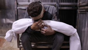 Conteúdo gráfico / Um homem palestino chora enquanto segura o corpo envolto em manto de uma criança, morta em ataques israelenses durante a noite, no necrotério do hospital Al-Shifa, na Cidade de Gaza, em 15 de julho de 2025. (Foto de Omar AL-QATTAA / AFP)