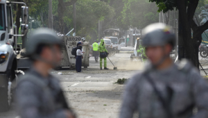 Funcionários de limpeza recolhem escombros em uma rua próxima à Escola Militar de Aviação Marco Fidel Suárez