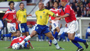 Durante a partida válida pelas oitavas-de-final da Copa do Mundo de 98, entre Brasil e Chile, Ronaldo (9) se estica todo para não perder a bola para Fuentes (3)