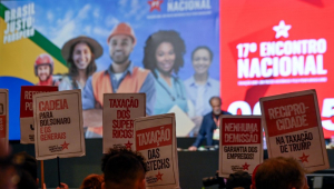 Militante petista levanta placa pedindo "reciprocidade na taxação de Trump" durante o 17º Encontro Nacional do Partido dos Trabalhadores, em Brasília