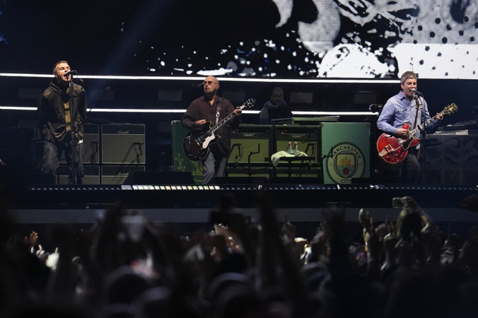 Liam Gallagher (vocalista), Paul Arthurs (guitarrista) e Noel Gallagher (vocalista e guitarrista) da banda britânica Oasis se apresentam no Principality Stadium, em Cardiff
