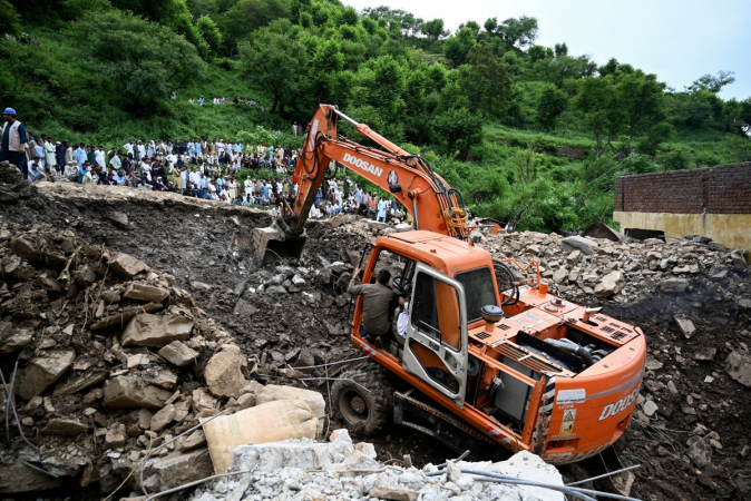 Equipes de socorro usam uma escavadeira para remover os escombros de casas desabadas enquanto buscam vítimas nos escombros, um dia após uma tempestade na vila de Dalori, no distrito de Swabi, na província montanhosa de Khyber Pakhtunkhwa, no Paquistão