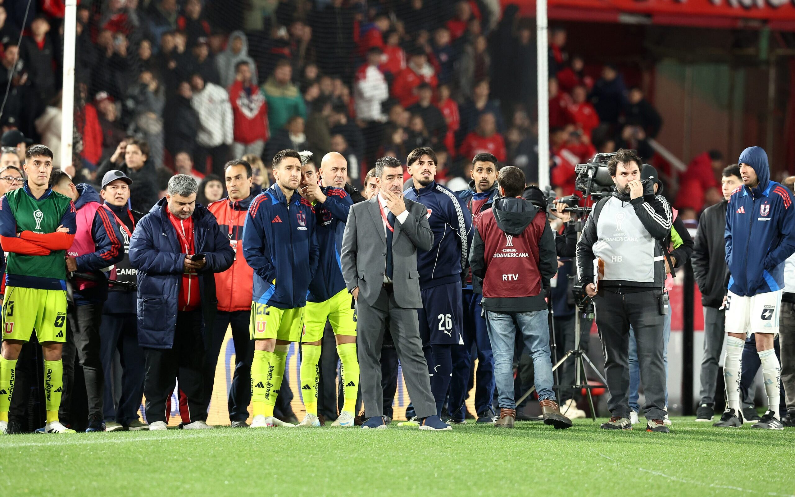 Jogadores da Universidad de Chile oberservão confusão nas arquibancadas com duelo com o Indepiendiente paralisado 