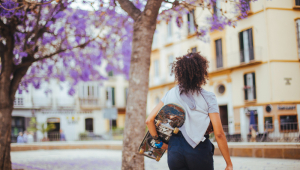 Menina segurando skate sob árvores