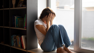 Retrato de jovem com baixa auto-estima sentado perto da janela em casa