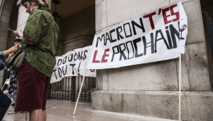 Uma mulher ao lado de uma faixa com os dizeres "Macron, você é o próximo" durante um protesto espontâneo após a rejeição do voto de confiança solicitado pelo primeiro-ministro François Bayrou