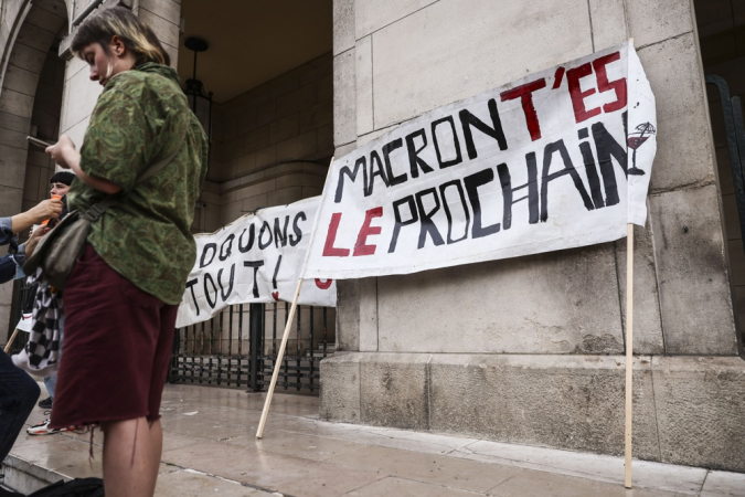 Uma mulher ao lado de uma faixa com os dizeres "Macron, você é o próximo" durante um protesto espontâneo após a rejeição do voto de confiança solicitado pelo primeiro-ministro François Bayrou