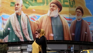 Mulher iraniana passa por um outdoor com imagens dos falecidos líderes do Hezbollah Hassan Nasrallah (C) e Sheikh Safieddine (D), junto ao falecido general do Corpo de Guardiões da Revolução Islâmica (IRGC) e comandante da Força Quds, Qasem Soleimani (E)