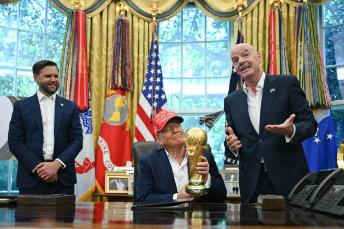 O presidente dos Estados Unidos, Donald Trump, ao lado do vice-presidente JD Vance (E) e do presidente da Fifa, Gianni Infantino (D), segura o troféu da Copa do Mundo