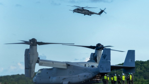 Fuzileiros navais dos Estados Unidos descarregam equipamentos de um V-22 Osprey enquanto um helicóptero Sikorsky CH-53K King Stallion sobrevoa o local, na chegada ao Aeroporto José Aponte de la Torre, antiga Estação Naval Roosevelt Roads, em Ceiba, Porto Rico