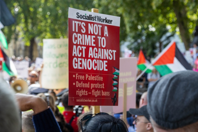 Apoiadores do grupo proibido Palestine Action seguram cartazes durante protesto de desobediência civil na Parliament Square, em Londres