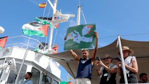 Um ativista mostra um mapa enquanto embarca em um barco, parte de uma flotilha civil que visa romper o bloqueio israelense à Faixa de Gaza, no porto de Barcelona, ​​em 31 de agosto de 2025. Uma flotilha com ajuda humanitária e ativistas deve partir de Barcelona em 31 de agosto de 2025 para tentar "romper o cerco ilegal de Gaza", disseram os organizadores. A flotilha deve chegar ao enclave costeiro devastado pela guerra em meados de setembro. (Foto de Lluis GENE / AFP)