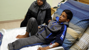Abdel Rahman Nawfal, de 12 anos, senta-se ao lado da avó em um hospital na cidade de Ramallah, na Cisjordânia, em 23 de abril de 2018, após ter sua perna amputada devido a um ferimento sofrido durante confrontos com forças israelenses perto da fronteira entre Gaza e Israel. (Foto de ABBAS MOMANI / AFP)