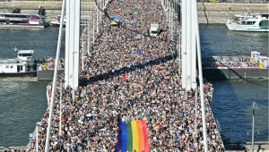 Pessoas carregam uma bandeira do arco-íris enquanto participam da Parada do Orgulho LGBTQIA+ no centro de Budapeste, em 28 de junho de 2025, quando a prefeitura da capital organizou esta marcha pela comunidade LGBTQIA+, celebrando a liberdade, em uma tentativa de burlar uma lei que permite à polícia proibir marchas LGBTQIA+. O primeiro-ministro húngaro anunciou que a polícia não "interromperá" a Parada do Orgulho LGBTQIA+ de sábado, apesar de ter emitido uma proibição, mas alertou os participantes e organizadores sobre as consequências legais. Sua coalizão governista alterou leis e a constituição no início deste ano para proibir a celebração anual, dando continuidade à sua repressão aos direitos LGBTQIA+, amplamente condenada e que já dura anos, em nome da "proteção à criança". (Foto de Attila KISBENEDEK / AFP)
