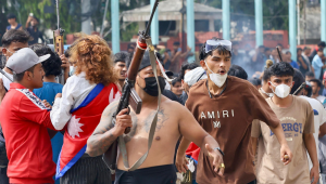 Um manifestante porta uma arma de fogo enquanto manifestantes se reúnem em frente ao complexo do palácio Singha Durbar durante um protesto para condenar a repressão policial contra manifestantes em Katmandu em 9 de setembro de 2025, um dia após manifestações contra a proibição de redes sociais e a corrupção governamental. O Nepal revogou sua proibição de redes sociais em 9 de setembro, um dia após pelo menos 19 pessoas terem sido mortas em protestos de jovens que exigiam que o governo suspendesse as restrições e combatesse a corrupção. Os protestos continuaram em 9 de setembro, desafiando o toque de recolher para expressar sua indignação com uma das repressões mais mortais contra manifestantes em anos — apesar de todos os principais aplicativos de redes sociais terem retomado suas operações online e do governo ter apelado por calma. (Foto de Prabin RANABHAT / AFP)