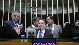 Hugo Motta sentado na cadeira da Câmara dos Deputados