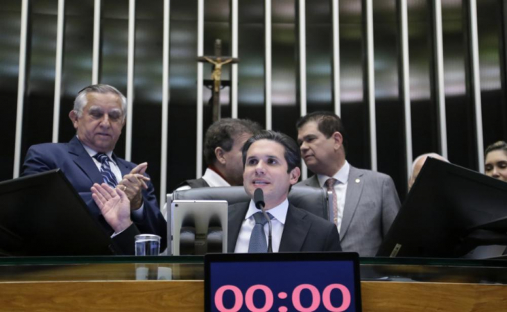 Hugo Motta sentado na cadeira da Câmara dos Deputados