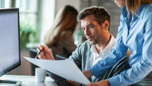Dois colegas de trabalho examinando documentos enquanto trabalhavam juntos no escritório