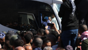 Um membro do Crescente Vermelho gesticula de dentro de um ônibus que transportava prisioneiros palestinos libertados ao chegarem após serem libertados de uma prisão israelense como parte do acordo de libertação entre Israel e Hamas, na cidade de Ramallah, na Cisjordânia, em 13 de outubro de 2025. Como parte do acordo de cessar-fogo entre Israel e Hamas, cerca de 20 prisioneiros israelenses e cerca de 2.000 prisioneiros palestinos estão programados para serem libertados em 13 de outubro. (Ramala) EFE/EPA/ALAA BADARNEH
