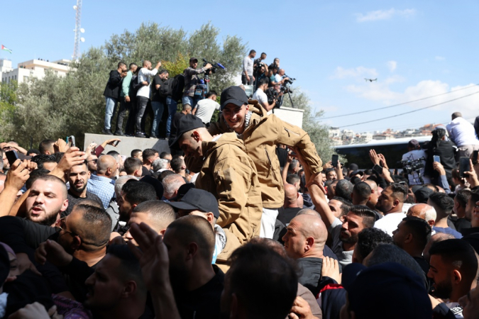 Pessoas cumprimentam prisioneiros palestinos libertados ao chegarem após serem libertados de uma prisão israelense como parte do acordo de libertação entre Israel e Hamas, na cidade de Ramallah, na Cisjordânia, em 13 de outubro de 2025. Como parte do acordo de cessar-fogo entre Israel e Hamas, cerca de 20 prisioneiros israelenses e cerca de 2.000 prisioneiros palestinos estão programados para serem libertados em 13 de outubro. (Ramala) EFE/EPA/ALAA BADARNEH