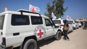 Um militante das Brigadas Qassam está ao lado de veículos do Comitê Internacional da Cruz Vermelha (CICV) enquanto se preparam para decolar com o segundo lote de reféns israelenses libertados pelo Hamas no sul de Deir el-Balah, no centro da Faixa de Gaza, em 13 de outubro de 2025. Israel disse que os últimos 20 reféns vivos libertados pelo Hamas em 13 de outubro chegaram ao país.