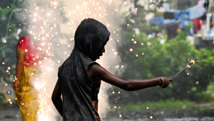 Um menino acende um fogo de artifício durante as celebrações na véspera de Diwali, o festival hindu das luzes, no alojamento de uma escola em Chennai, em 19 de outubro de 2025. (Foto de R. Satish BABU / AFP)