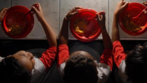 Crianças seguram prato de comida