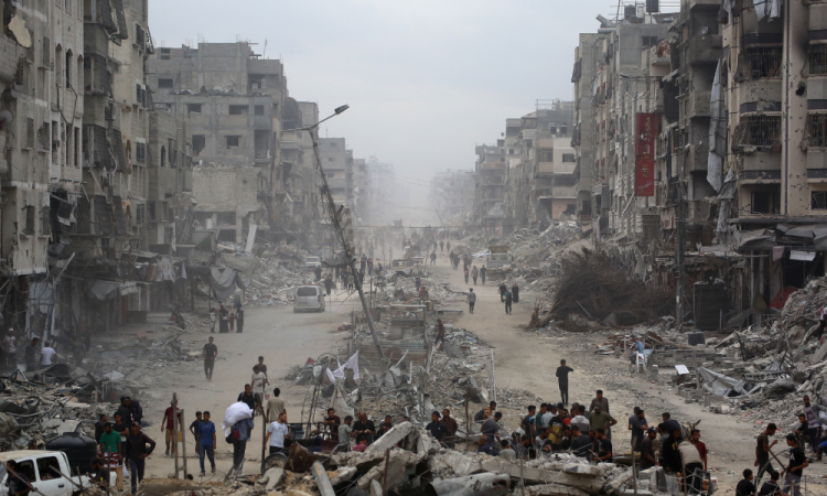 Centenas de milhares de palestinos retornaram à devastada Cidade de Gaza após a entrada em vigor do cessar-fogo entre Israel e o Hamas, enquanto ambos os lados discutem a implementação do plano de 20 pontos do presidente dos EUA, Donald Trump, para encerrar a guerra, que exige o desarmamento do Hamas e que o grupo não se envolva na administração de Gaza no pós-guerra. Palestinos passam por prédios destruídos na Cidade de Gaza em 12 de outubro de 2025.