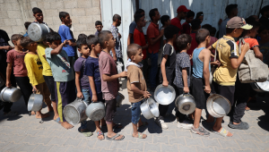 IMAGEM PRINCIPAL - Palestinos fazem fila para receber uma refeição quente de uma cozinha beneficente no campo de refugiados de Nuseirat, na Faixa de Gaza sitiada por Israel, em 11 de setembro de 2025, em meio a uma situação de fome declarada pela ONU após quase dois anos de guerra. (Foto de Eyad BABA / AFP)