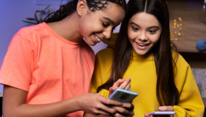 Duas adolescentes mandando mensagens de texto juntas em casa em smartphones