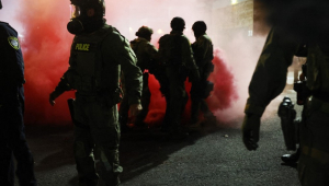 Agentes federais, incluindo membros do Departamento de Segurança Interna, da Patrulha de Fronteira e da polícia, tentam conter manifestantes em frente a uma unidade do Serviço de Imigração e Alfândega dos Estados Unidos