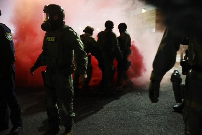 Agentes federais, incluindo membros do Departamento de Segurança Interna, da Patrulha de Fronteira e da polícia, tentam conter manifestantes em frente a uma unidade do Serviço de Imigração e Alfândega dos Estados Unidos