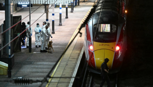 Policiais e um agente canino trabalham na plataforma na estação de Huntingdon, em Huntingdon, leste da Inglaterra, após um esfaqueamento em um trem