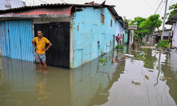 Hhomem em meio às águas da enchente do lado de fora de sua casa em Wellampitiya, nos arredores de Colombo, no Sri Lanka