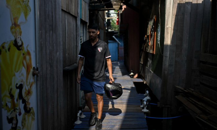 Um homem vestindo a camisa do time de futebol São Paulo caminha pela Vila da Barça, um bairro de palafitas em Belém, no Pará, Brasil, em 5 de novembro de 2025. (Foto de Mauro PIMENTEL / AFP)