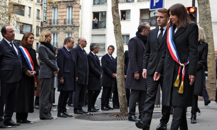 O presidente francês Emmanuel Macron (2º à direita) e a prefeita de Paris, Anne Hidalgo (à direita), chegam para prestar homenagem às vítimas em frente ao bar "La Belle Equipe", em Paris, em 13 de novembro de 2025, durante as cerimônias que marcaram uma década desde os ataques terroristas de 13 de novembro de 2015, nos quais 130 civis foram mortos. (Foto de Ludovic MARIN / POOL / AFP)