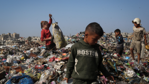 Crianças palestinas deslocadas procuram itens que possam ser usados ​​como combustível para cozinhar, em meio a uma pilha de lixo ao lado de prédios destruídos no campo de refugiados de Bureij, na região central da Faixa de Gaza, em 23 de novembro de 2025. (Foto de EYAD BABA / AFP)