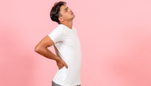 Vista frontal jovem do sexo masculino tendo dor nas costas na cor de fundo rosa modelo emoção masculino