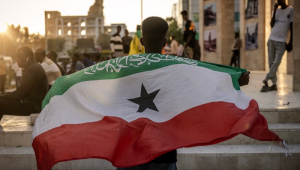 Homem segura a bandeira da Somalilândia em frente ao Memorial da Guerra de Hargeisa
