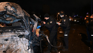 Policiais ucranianos inspecionam um carro destruído com o corpo de uma vítima no local do impacto após um ataque em Kharkiv