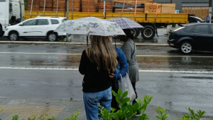Pedestres se protegem da chuva em ponto de ônibus no bairro de Interlagos, na zona sul de São Paulo