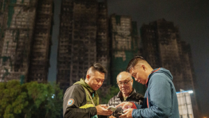 Foto mostra Yip Ka-kui (no centro) e seus filhos Yip Shun-ting e Yip Shun-yin olhando fotos antigas de sua esposa, Pak Shui-lin, enquanto relembram momentos felizes em sua casa, perto do conjunto residencial Wang Fuk Court
