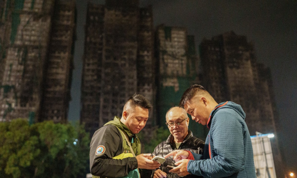 Foto mostra Yip Ka-kui (no centro) e seus filhos Yip Shun-ting e Yip Shun-yin olhando fotos antigas de sua esposa, Pak Shui-lin, enquanto relembram momentos felizes em sua casa, perto do conjunto residencial Wang Fuk Court