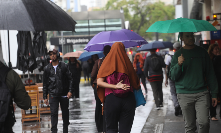 Pedestres se protegem da chuva na Avenida Paulista, na região centro-sul da cidade de São Paulo, na manhã desta quarta-feira (17)