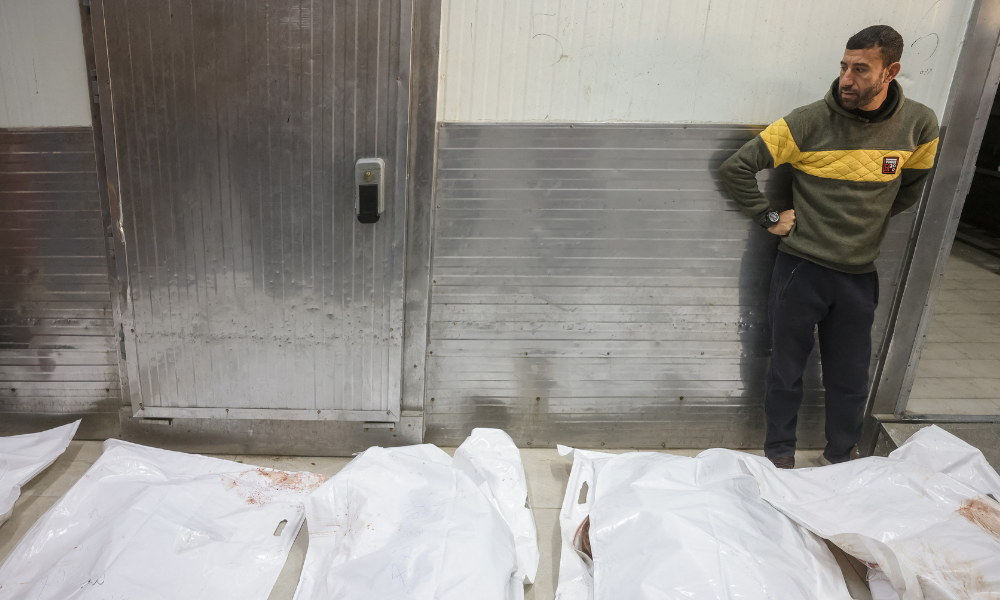 Um homem está ao lado de sacos brancos para cadáveres durante o funeral de palestinos mortos em 3 de dezembro por um ataque israelense, no Hospital Nasser em Khan Yunis, no sul da Faixa de Gaza, em 4 de dezembro de 2025. A agência de defesa civil de Gaza disse à AFP em 3 de dezembro que um ataque israelense no sul do território palestino matou cinco pessoas, incluindo duas crianças. Os militares israelenses disseram que atacaram um militante do Hamas no sul de Gaza em resposta a um confronto com combatentes palestinos na área, que deixou cinco soldados feridos.