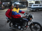 Mototaxista vestindo uma jaqueta com a bandeira da Venezuela transporta um passageiro nos arredores da prisão El Rodeo I em Guatire, estado de Miranda, a cerca de 30 quilômetros a leste de Caracas
