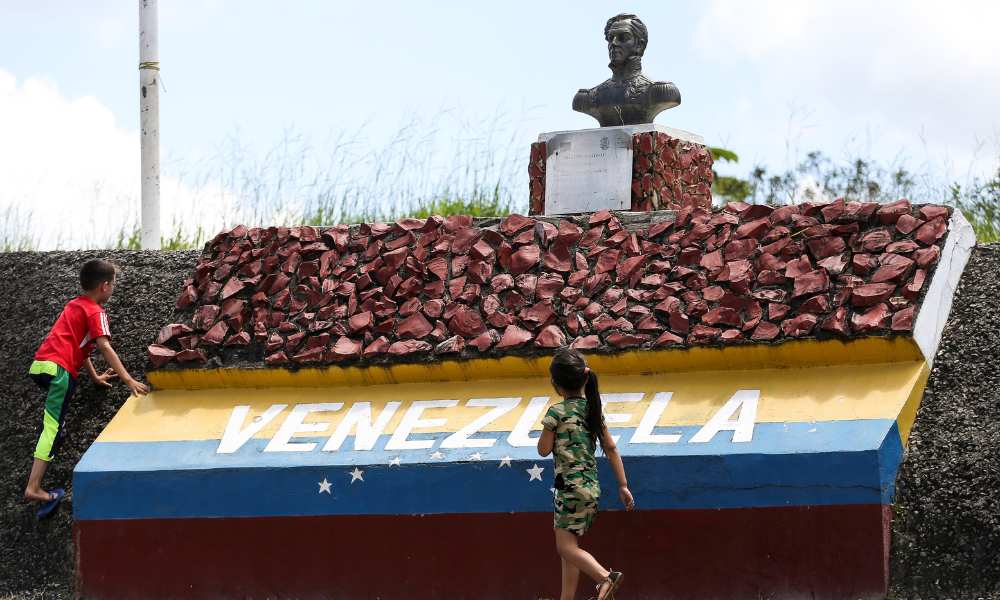 Crianças brincam em marco da fronteira entre Brasil e Venezuela.